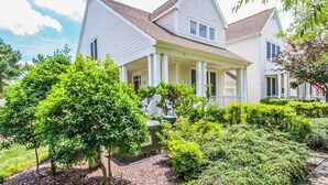 A two-story house with a front porch, surrounded by well-maintained greenery. - Bear Trap Dunes townhouse w/ gym, pool, free WiFi, and golf on-site (Ocean View)