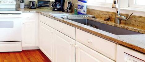 A kitchen with white cabinets, a stainless steel sink, a coffee maker, and a toaster.