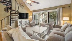 A living room with a sofa, coffee table, TV, and a ceiling fan. - Sea Colony tennis condo with pool, hot tub, sauna, & fitness room (Bethany Beach)