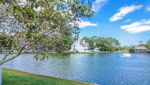 Un lago tranquillo con una casa sullo sfondo, immerso nel verde.
