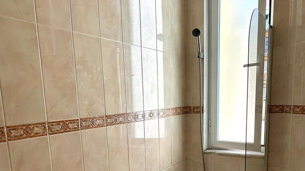 A bathroom with a bathtub, a shower, and a window. - Palmira (Lisbon)