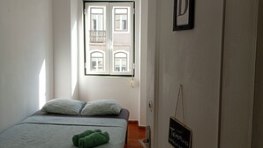 Une chambre à coucher avec un lit, des oreillers, une fenêtre, une porte et une pancarte de bienvenue.