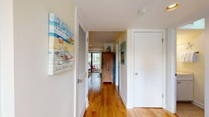 Un couloir avec un plancher en bois, des portes blanches et un tableau encadré accroché au mur.