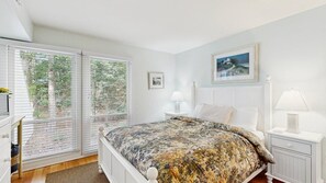 Une chambre à coucher avec un lit, des tables de chevet, une fenêtre avec des stores et un tableau encadré au mur.