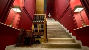 Un magnifique escalier avec un mur rouge, une balustrade blanche et un plafond décoratif.