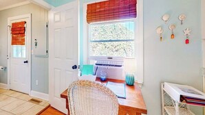 A room with a wooden desk, a wicker chair, a window with blinds, a radiator, and a wall-mounted shelf with decorative items. - Town of Rehoboth Beach home in a great location with yard and 3-season room (Rehoboth Beach)