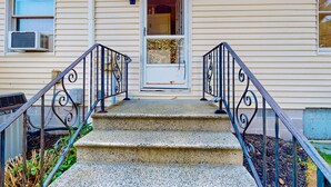 A house with a front porch, a set of concrete steps, and a black metal railing. - Town of Rehoboth Beach home in a great location with yard and 3-season room (Rehoboth Beach)