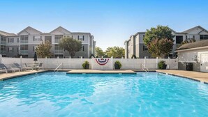 A swimming pool with a white fence, lounge chairs, and a flag. - Villas at Bay Crossing - perfectly appointed with pool & patio - beaches nearby (Lewes)