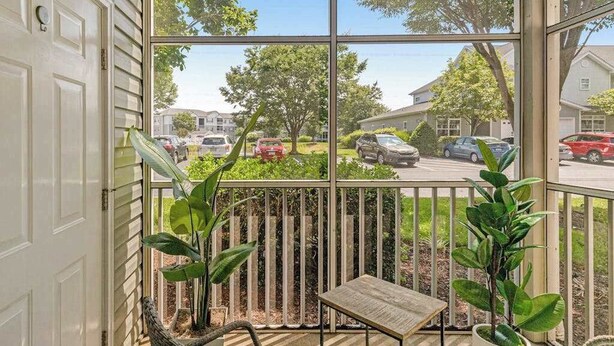 A covered porch with a table and chairs, a view of a street with parked cars, and a wooden fence. - Villas at Bay Crossing - perfectly appointed with pool & patio - beaches nearby (Lewes)