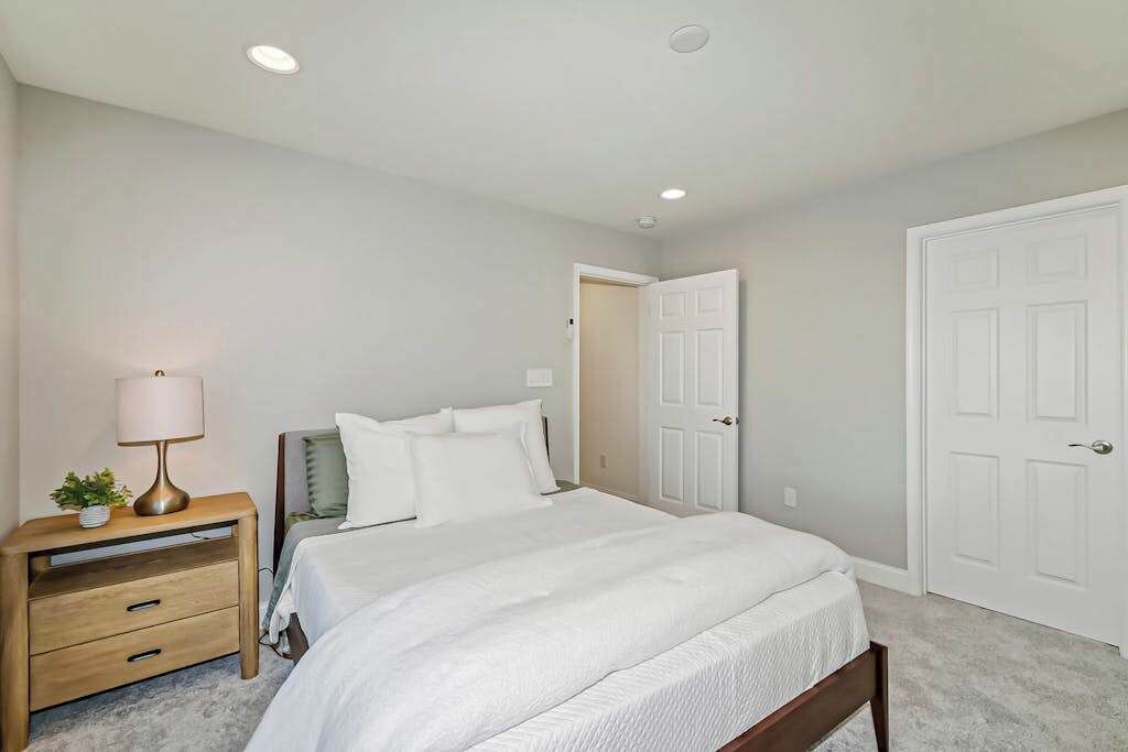 A bedroom with a bed, nightstand, lamp, and two doors.
