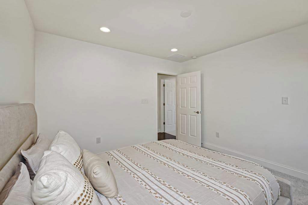 A bedroom with a bed, pillows, a door, and a ceiling light.