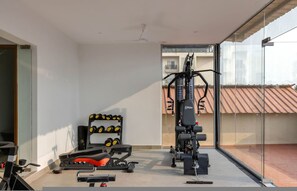 A modern gym with exercise equipment, a bench, and dumbbells. - Field View 2bhk Retreat 1km to Candolim Beach (Candolim)
