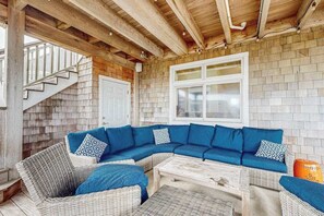 A covered outdoor seating area with a wooden ceiling, a white door, and a brick wall. - The Chancellery pet friendly house with private patio, balcony & grill (Dewey Beach)