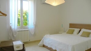 A bedroom with a bed, a window with curtains, a radiator, and a hanging light fixture. - Villa le Muse - beautiful detached villa with swimming pool, (Marsala)