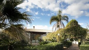 A pathway leading to a building with a tiled roof, surrounded by lush greenery and palm trees. - Villa le Muse - beautiful detached villa with swimming pool, (Marsala)