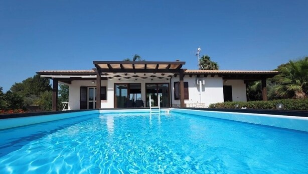 A swimming pool with a covered area, surrounded by greenery and a clear sky. - Villa le Muse - beautiful detached villa with swimming pool, (Marsala)