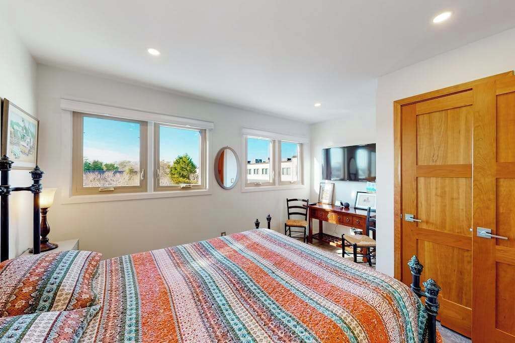 A bedroom with a bed, a desk, a chair, a TV, and a wardrobe.