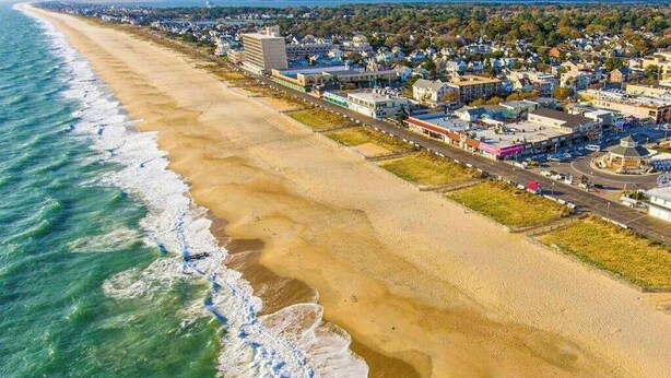 An aerial view of a coastal town with a beach, buildings, and roads. - Upgraded home with pools, sports courts, bikes, chef's kitchen, firepit, & gym (Rehoboth Beach)