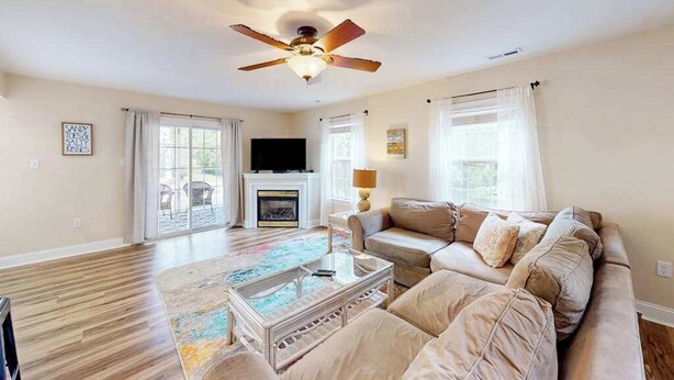 A spacious living room with a ceiling fan, a fireplace, a sofa, and a coffee table. - Eagles Landing home with gas fireplace, washer/dryer, pool & tennis court (Rehoboth Beach)