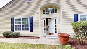 A two-story house with a front door, a small porch, and a large potted plant. - Eagles Landing home with gas fireplace, washer/dryer, pool & tennis court (Rehoboth Beach)
