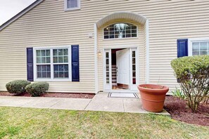 A two-story house with a front door, a small porch, and a large potted plant. - Eagles Landing home with gas fireplace, washer/dryer, pool & tennis court (Rehoboth Beach)
