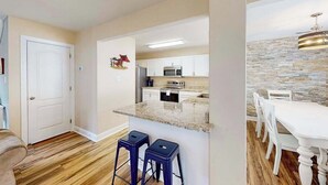 A modern kitchen with white cabinets, a granite countertop, and a stone backsplash. - Eagles Landing home with gas fireplace, washer/dryer, pool & tennis court (Rehoboth Beach)