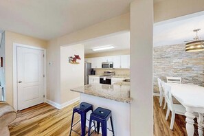A modern kitchen with white cabinets, a granite countertop, and a stone backsplash. - Eagles Landing home with gas fireplace, washer/dryer, pool & tennis court (Rehoboth Beach)