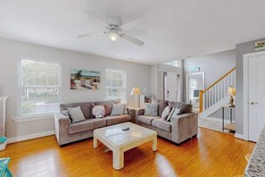 A living room with two sofas, a coffee table, a ceiling fan, and a staircase. - Home near the ocean with a pool, outdoor space, WiFi, central AC, & washer/dryer (Rehoboth Beach)