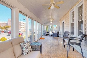 Eine überdachte Veranda mit einer Couch, Sesseln und einem Deckenventilator.