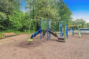 A playground with climbing structures and slides, surrounded by trees. - Coastal Escape with Incredible Sunsets – Boat, Fish & Play at Angola By The Bay! (Lewes)