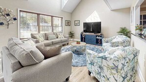 Una sala de estar moderna con un sofá, sillones, un televisor y una alfombra azul estampada.