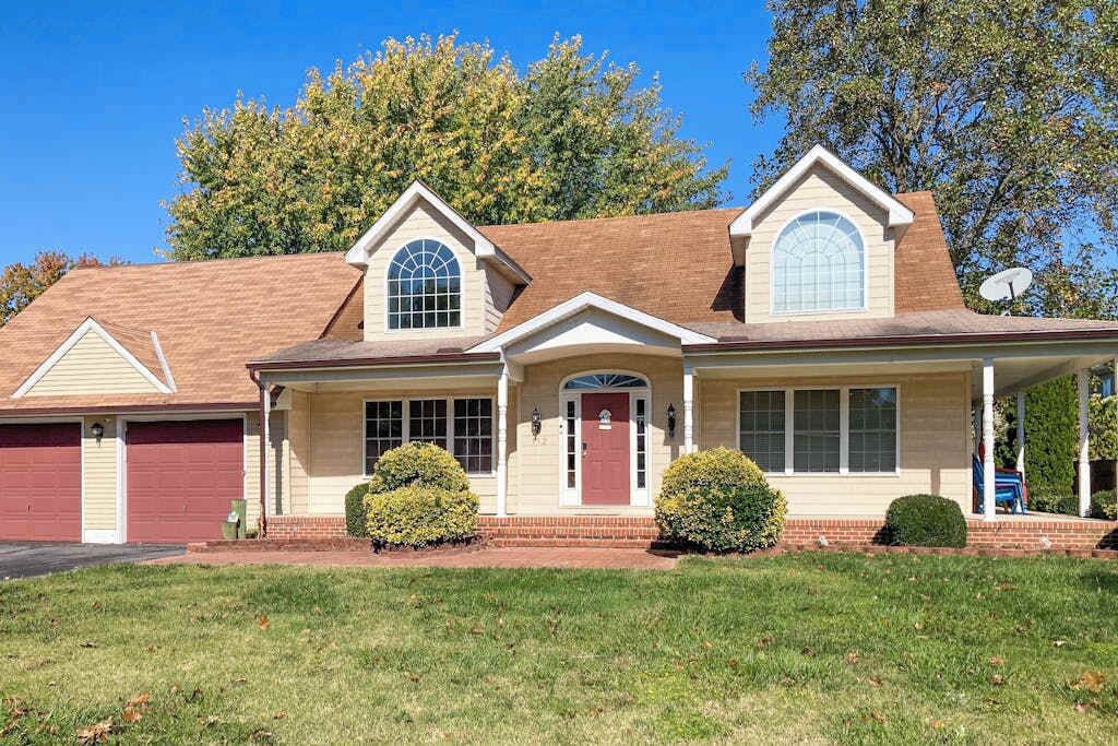 A two-story house with a red garage, a front porch, and a satellite dish.