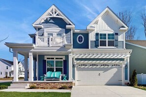 A two-story house with a covered porch, a garage, and a small front yard. - Arbor-Lyn house with shared pool, fire pit, deck & gas grill (Rehoboth Beach)