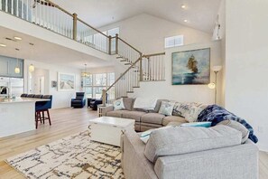 A spacious living area with a staircase, a kitchen, and a dining area. - Arbor-Lyn house with shared pool, fire pit, deck & gas grill (Rehoboth Beach)
