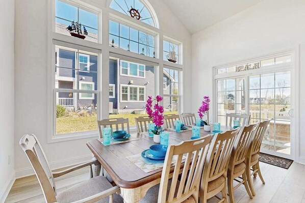 A dining area with a large table, chairs, and large windows. - Arbor-Lyn house with shared pool, fire pit, deck & gas grill (Rehoboth Beach)