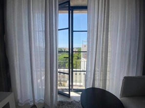 A room with a view through a glass door, a white sofa, and a small rug. - Casa Amanhada - Apartment One (Grândola)