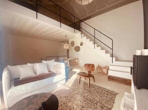 A modern interior with a staircase, a sofa, a coffee table, and a rug. - Casa Amanhada - Apartment One (Grândola)