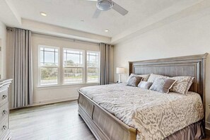 A bedroom with a large bed, a ceiling fan, a dresser, and a window with curtains. - Oyster House Village house w/community pool, private hot tub, kayaks (Rehoboth Beach)