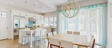 A modern kitchen with white cabinets, a central island, and pendant lighting.