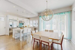 A modern kitchen with white cabinets, a central island, and pendant lighting. - Town of Rehoboth Beach house w/private pool, patio, grill, walk to beach (Rehoboth Beach)
