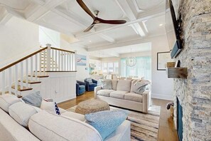 A spacious living area with a staircase, a fireplace, and a dining area in the background. - Town of Rehoboth Beach house w/private pool, patio, grill, walk to beach (Rehoboth Beach)