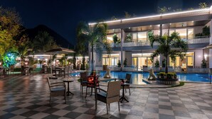 Un hotel con piscina, mobiliario exterior y vistas a la montaña.