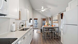 A modern kitchen with a built-in oven, a sink, and a dining area with wooden stools. - Dog-friendly Rehoboth Beach cottage steps from the beach & boardwalk (Rehoboth Beach)