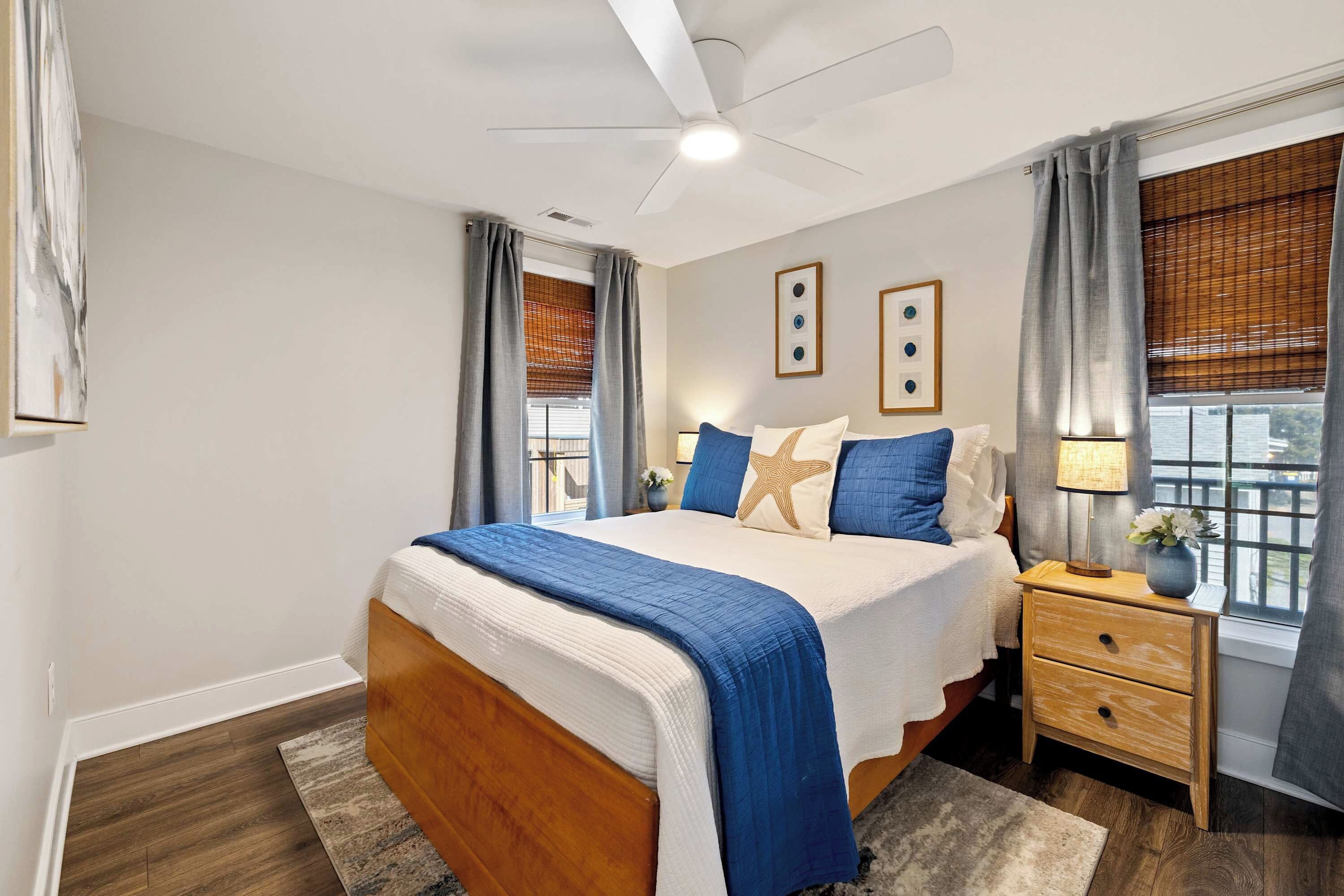 A bedroom with a bed, nightstands, a ceiling fan, and a window with curtains.