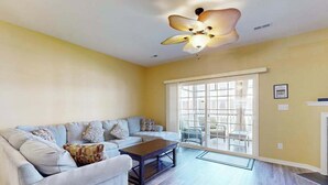 Un salon avec un canapé, une table basse et un ventilateur de plafond.