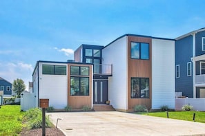 Een modern herenhuis met twee verdiepingen, een voordeur, een zichtbare trap en een kleine voortuin.