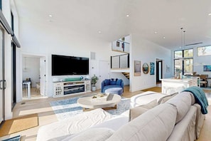 Een moderne woonkamer met een flatscreen televisie, een bank, een salontafel en een trap naar een verdieping erboven.