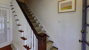 A staircase with wooden handrails, a white door, and a framed picture on the wall.