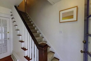A staircase with wooden handrails, a white door, and a framed picture on the wall. - Town of Rehoboth Beach apartment w/patio, grill, 2 blocks from beach (Rehoboth Beach)