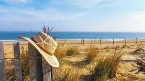 A beach scene with a wooden fence and a straw hat leaning against it. - Rehoboth Beach dog-friendly, hot tub, game room, and Washer/Dryer (Rehoboth Beach)